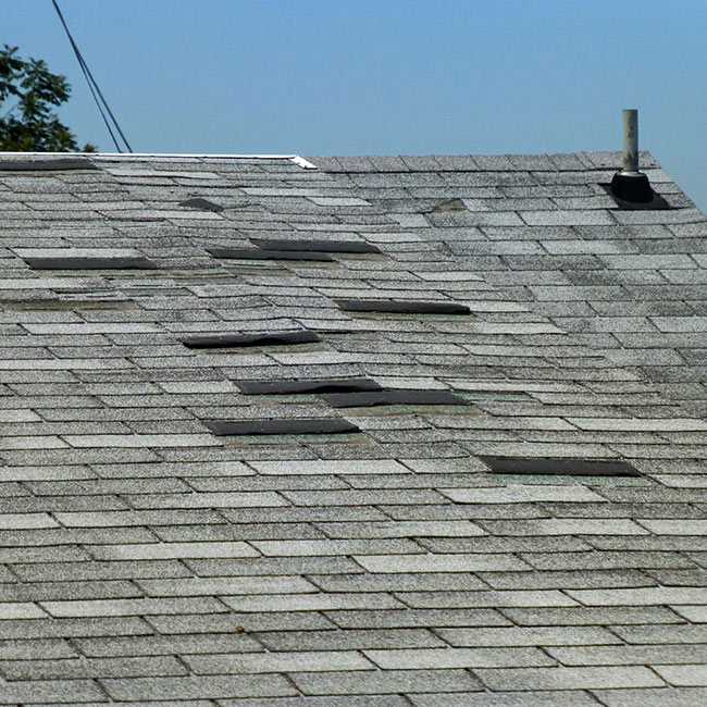 close up of a roof with loose shingles after storm damage lansing mi